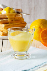 Lemon-tangerine curd in a glass gravy boat, tangerine and lemon and Belgian waffles.