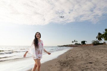 A day at the beach, woman smiling while a plane flys overhead.