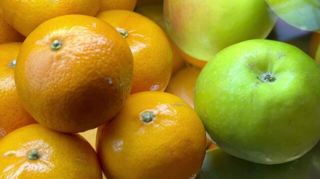 Juicy green apples and yellow oranges in the supermarket window are sold to customers. Close-up.