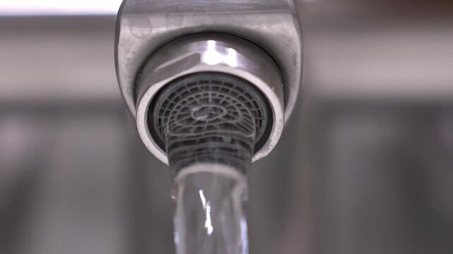 Stainless steel faucet releasing precise water stream, gradually slowing down and stopping, highlighting water conservation principles in contemporary residential setting