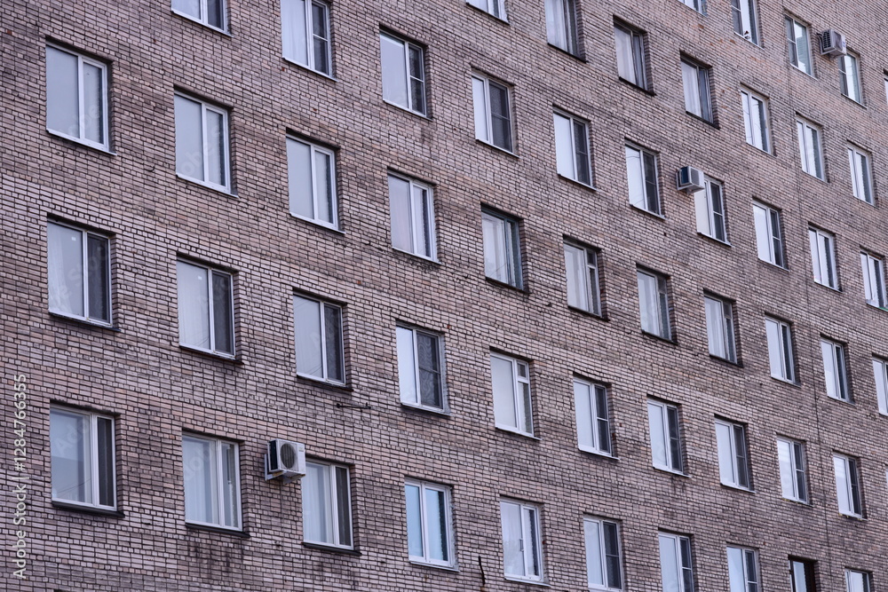 Poster a photograph of a tall brick building with many windows.