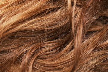 Hair background. Closeup of a woman's hair. Beautifully styled brown hair with natural shine and soft curls. Wavy hairstyle pattern.
