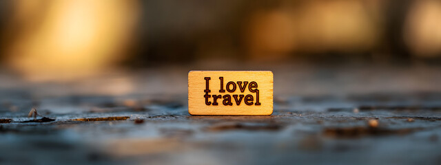 A small wooden label with the words "I love travel" written on it
