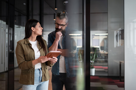 Creative millennials, casual business team, small business owners, working on social media strategy and brand development with a digital tablet in a modern, open space startup office