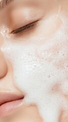 Fototapeta premium Woman applying facial cleanser, white foamy texture covering skin, highlighting skincare routine for clean, radiant complexion