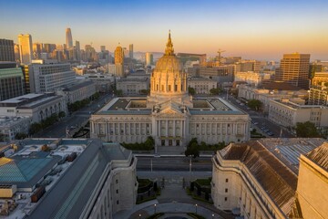 Fototapeta premium San Francisco City Hall at sunrise, showcasing the iconic building's architecture and the vibrant city skyline. Pride flags adorn the building. San Francisco, California, USA