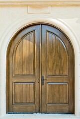 Arch top oak door in beige stucco wall