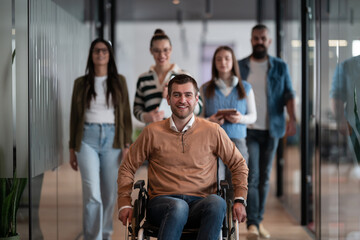 A businessman with disability in a wheelchair is surrounded by supportive colleagues in a modern...