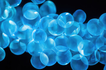 Abstract close-up of translucent blue spheres illuminated against a dark background, creating a mesmerizing and ethereal visual effect.