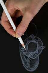 The work of a jeweler-designer. A jewelry designer develops sketches of jewelry. The process of drawing jewelry on a black surface.  Design studio. Creative ideas