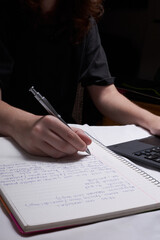Young woman studying with books and taking notes on paper, focused on learning and academic success in a quiet study environment.