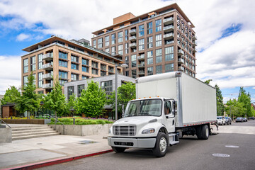 Popular local delivery and moving day cab middle duty semi truck with box trailer standing on the...