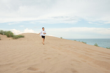 Boy Running Barefoot Up Sandy Dune Near Ocean, Freedom and Adventure Concept on Beach Landscape