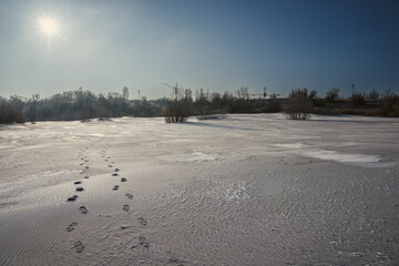 Sand quarry in th Vilnohirsk , Ukraine. Winter landscape on the sand quarry ,sun rays on the sy , beautiful colors on the picture . Path on the sand . Road and trees with lights of the sun . Trees 