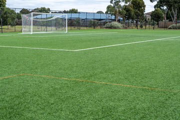 Background texture of a vacant full-sized artificial turf soccer field, complete with white...