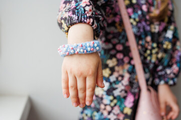 Handmade designer bracelet made of blue yarn and beads on a child's hand close-up. Creativity with children. Stylish childhood.