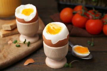 Soft boiled eggs and tomatoes on wooden table, selective focus