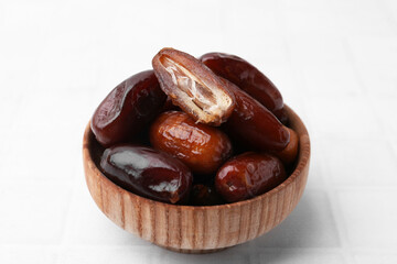 Tasty dried dates in bowl on white table, closeup