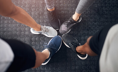 Fitness, group or huddle with shoes at gym in circle for teamwork, workout or unity at indoor...