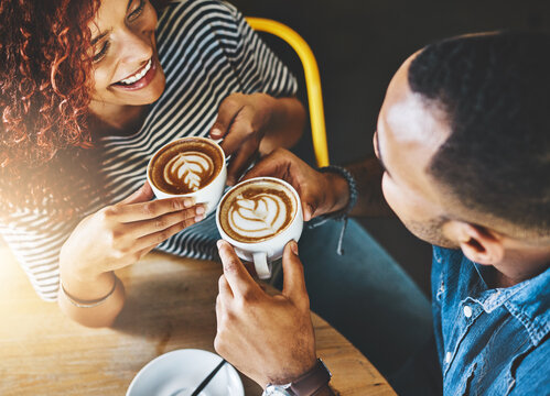 Coffee, conversation and couple on date in cafe for morning catch up together with bonding. Love, happy and young woman and man drinking cappuccino with latte art for romance in diner from above.