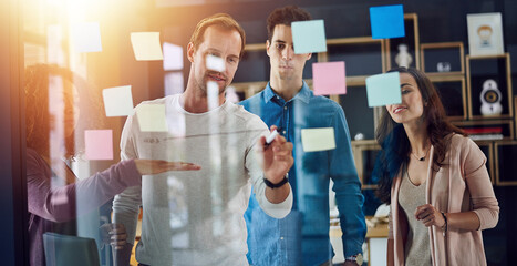 Business people, writing and brainstorming with team for project, schedule planning or meeting on glass board at office. Male person, employees or training group for agenda, tasks or work delegation