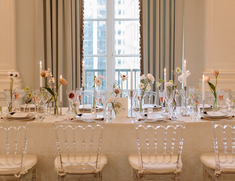 Elegant dining table set with flowers and candles in a bright room with large windows