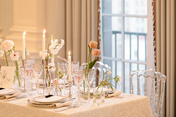 Elegant dining table set with candles and flowers in a bright, stylish interior during an afternoon gathering