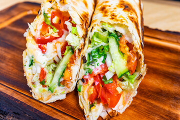 Grilled wrap filled with fresh vegetables and herbs on a wooden board