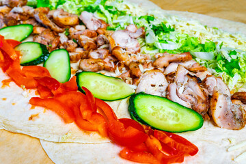 Grilled chicken wrap preparation with fresh vegetables and toppings