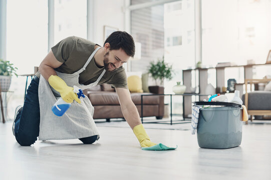 Happy man, cleaning and floor with spray bottle for housekeeping, chores or tidying at home. Male person, cleaner or maid with detergent, gloves or bucket of supplies for bacteria or germ removal