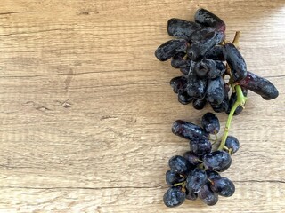 A bunch of Black Sweet Sapphire Grapes or Witch Grapes seedless elongated shaped with a fruit tip resembling a navel isolated on a rustic brown background