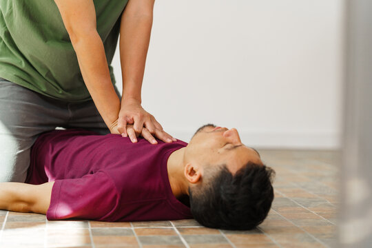 A woman performs chest compressions, administering CPR to an unconscious young man, demonstrating life-saving skills, emergency response, first aid, and medical assistance in a critical situation