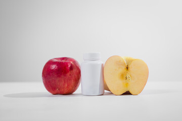 A supplement bottle and a fresh apple placed on the table, symbolizing health and nutrition, representing dietary choices, wellness, and natural or medical supplementation for a balanced lifestyle