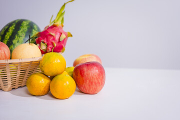 A rattan basket filled with colorful, fresh fruits is placed on a table. Fruits, rich in fiber, vitamins, and antioxidants, are essential for health, promoting body function and slowing down aging.