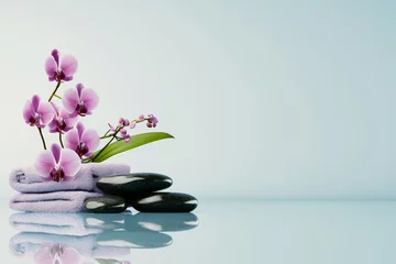 A serene arrangement of pink orchids and smooth black stones on a soft towel, evoking a tranquil spa atmosphere.