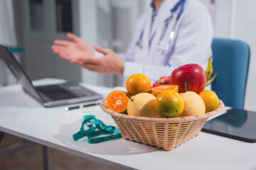 A male nutritionist works at his desk, discussing the benefits of eating fruit. He analyzes diets and educates patients on healthy eating habits for optimal health and well-being