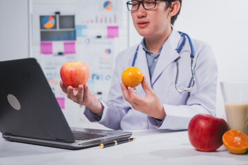 A male nutritionist works at his desk, discussing the benefits of eating fruit. He analyzes diets...