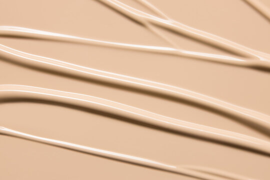 Makeup foundation cream texture background. Beige concealer, BB cream smeared