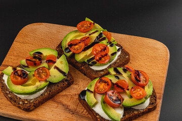 Delicious open-faced sandwiches with tomatoes and avocado on dark bread