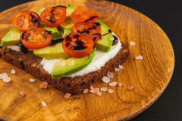 Sliced avocado and cherry tomatoes served on rye bread with salt