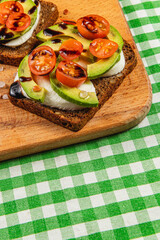 Delicious avocado and tomato toast served on dark bread with balsamic drizzle