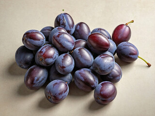 Fototapeta premium A small pile of damson resting on a soft, light beige surface.