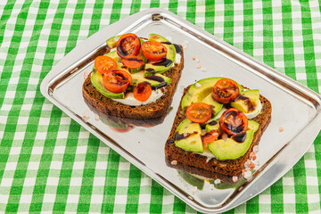 Delicious avocado toast with cherry tomatoes served on a tray