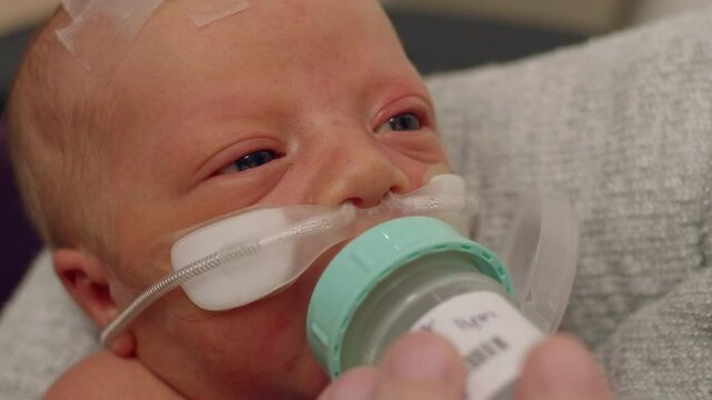 Newborn Baby Drinking from a Bottle While at the NICU While Being Held