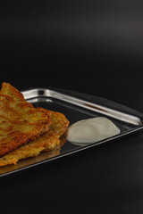 Crispy savory pancakes with creamy dip served on a sleek metal tray