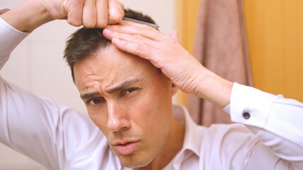 Sexy and very attractive man combing his hair