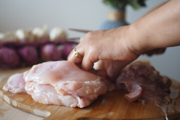 Cutting chicken on a wooden board in a home kitchen setting
