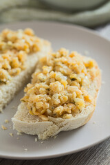 Fresh homemade vegan spread or salad made with split red lentil, onion, garlic and parsley, served on fresh homemade bread on plate (Selective Focus, Focus one third into the image)