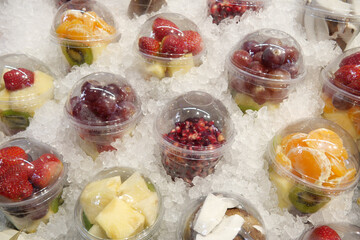 Fresh fruit cups arranged on ice at a market stall