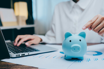 Young Professional Saving Money with Blue Piggy Bank and Laptop, business concept